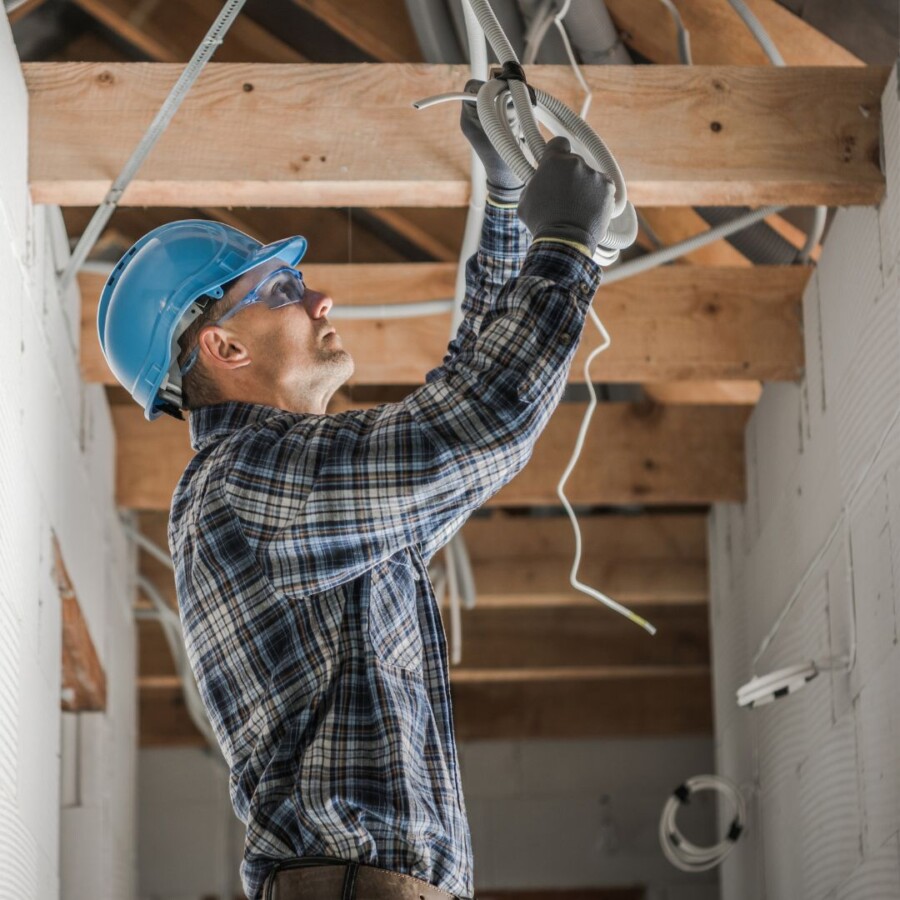 Construction worker installing electrical cabling inside a building under renovation, illustrating on‑site risks covered by contractors liability insurance.