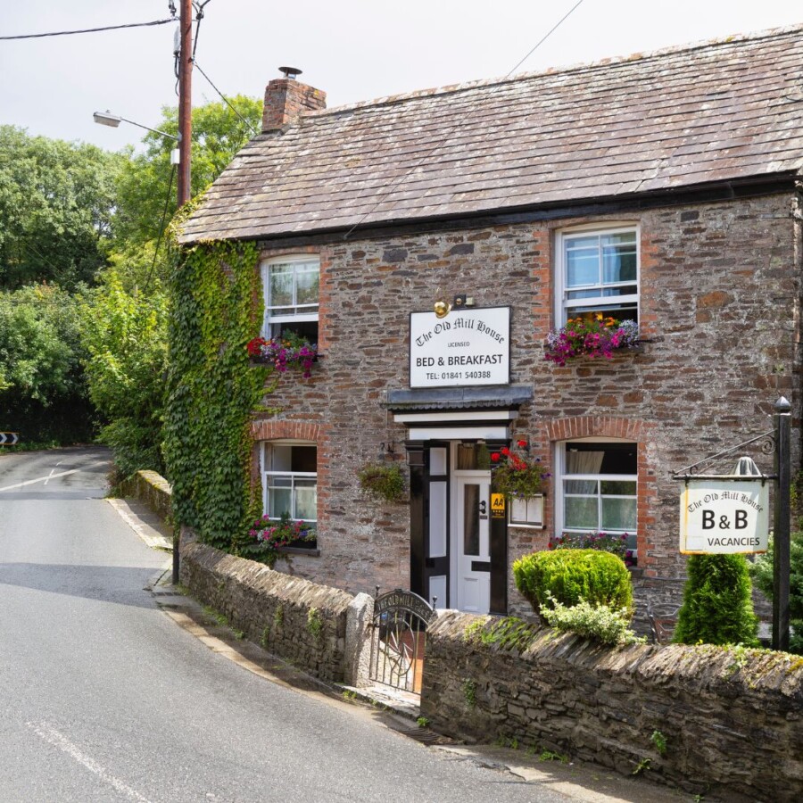 Traditional stone bed and breakfast building with signage, flowers and a roadside entrance, representing guest houses and small hotels covered Hotels and Guest Houses Insurance.